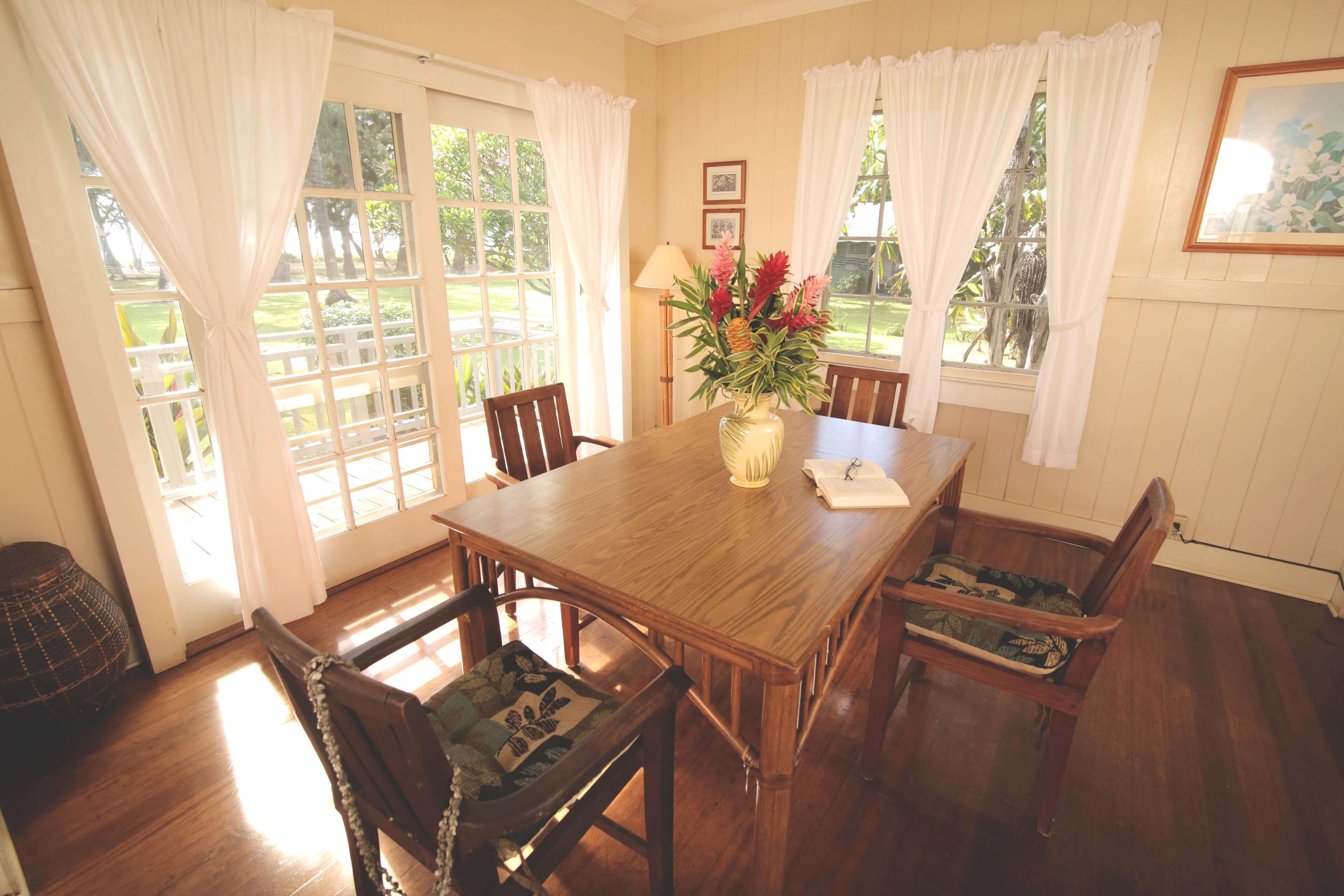 A dining room with a wooden table and chairs, a vase with flowers, and a lamp.