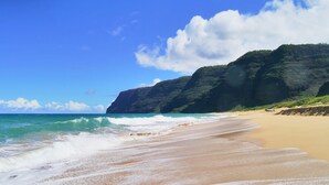 A beach with waves, a clear sky, and a mountain in the background. - Waimea Plantation Cottages, a Coast Resort (Waimea)
