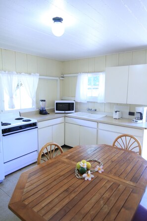 A kitchen with a stove, microwave, sink, and a dining table with chairs.