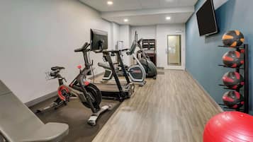 A gym with treadmills, stationary bikes, and exercise balls.