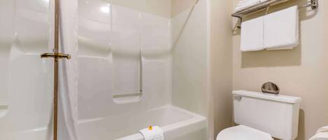 A bathroom with a bathtub, toilet, and a towel rack.