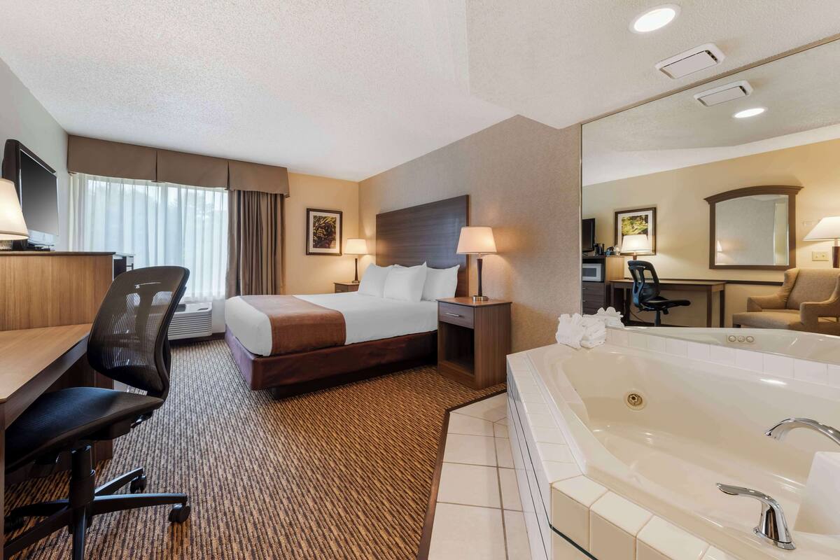 Une chambre d’hôtel équipée d’un lit, d’un bureau, d’une chaise et d’une grande baignoire.