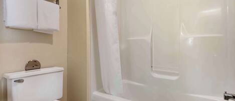 A bathroom with a toilet, a bathtub, and a shower curtain.