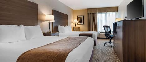 Ein Hotelzimmer mit zwei Betten, einem Schreibtisch, einem Stuhl, einem Fernseher und einer Lampe.