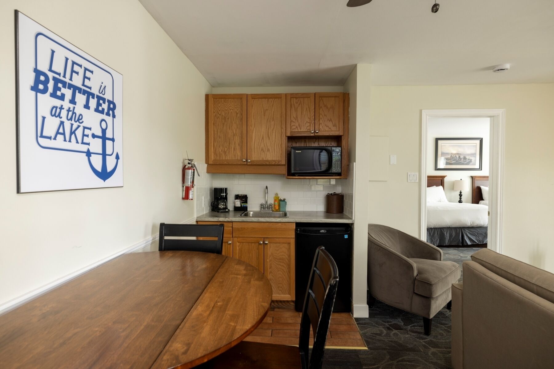 A compact hotel room with a kitchenette, a dining area, and a bed.