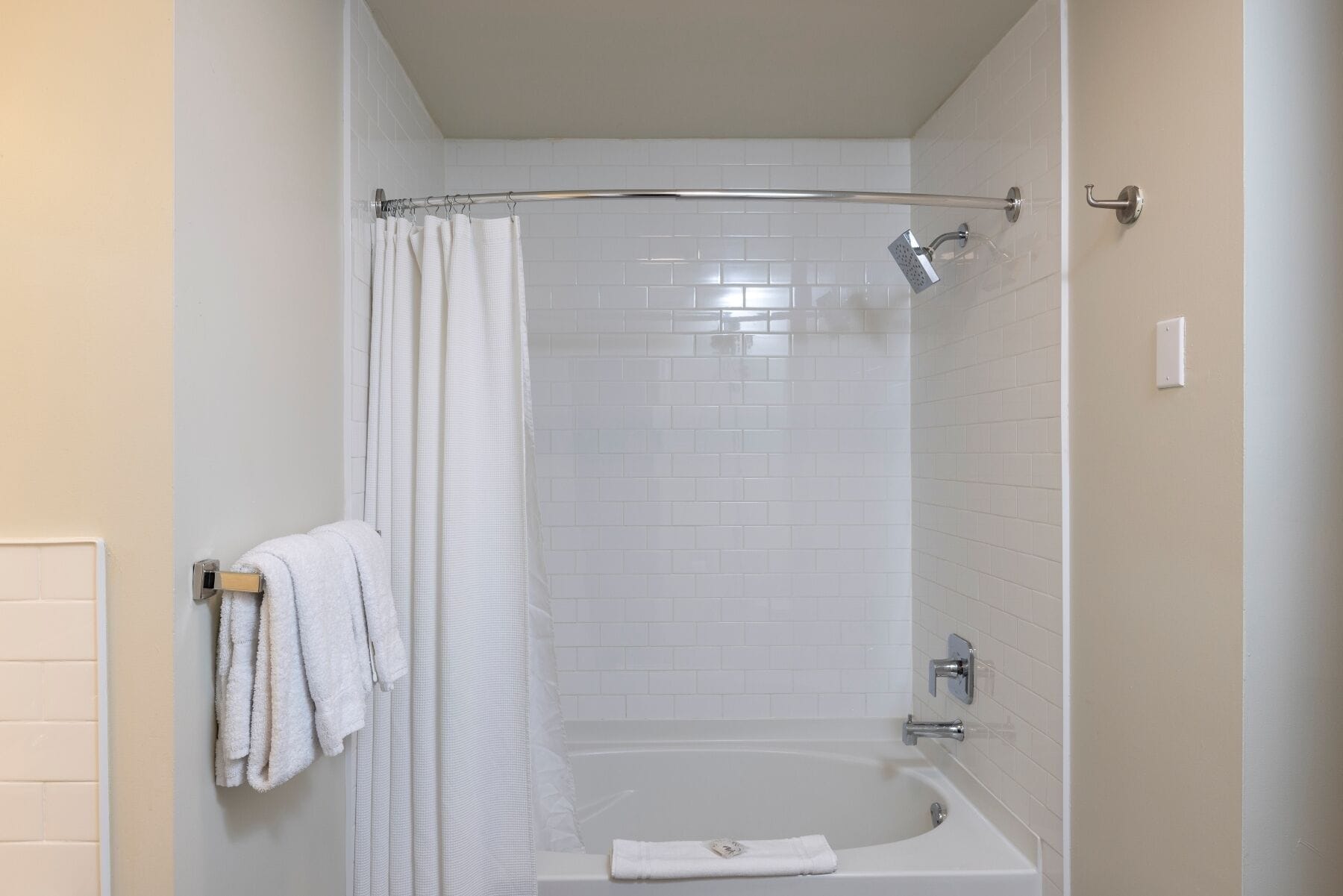 Un baño moderno con una bañera blanca, una ducha con puerta de cristal y un perchero con toallas.