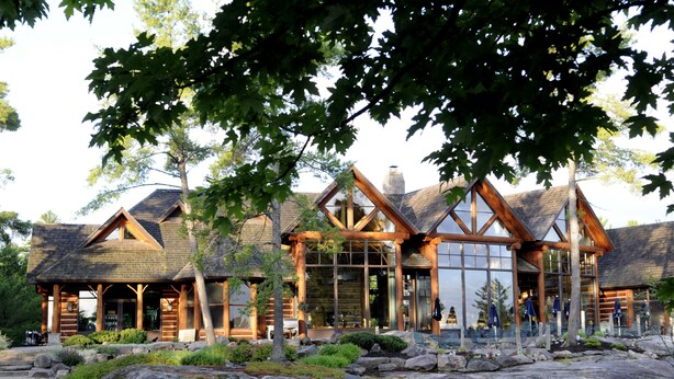 A log cabin with a stone foundation, large windows, and a stone roof. - Rocky Crest Golf Resort (Seguin)