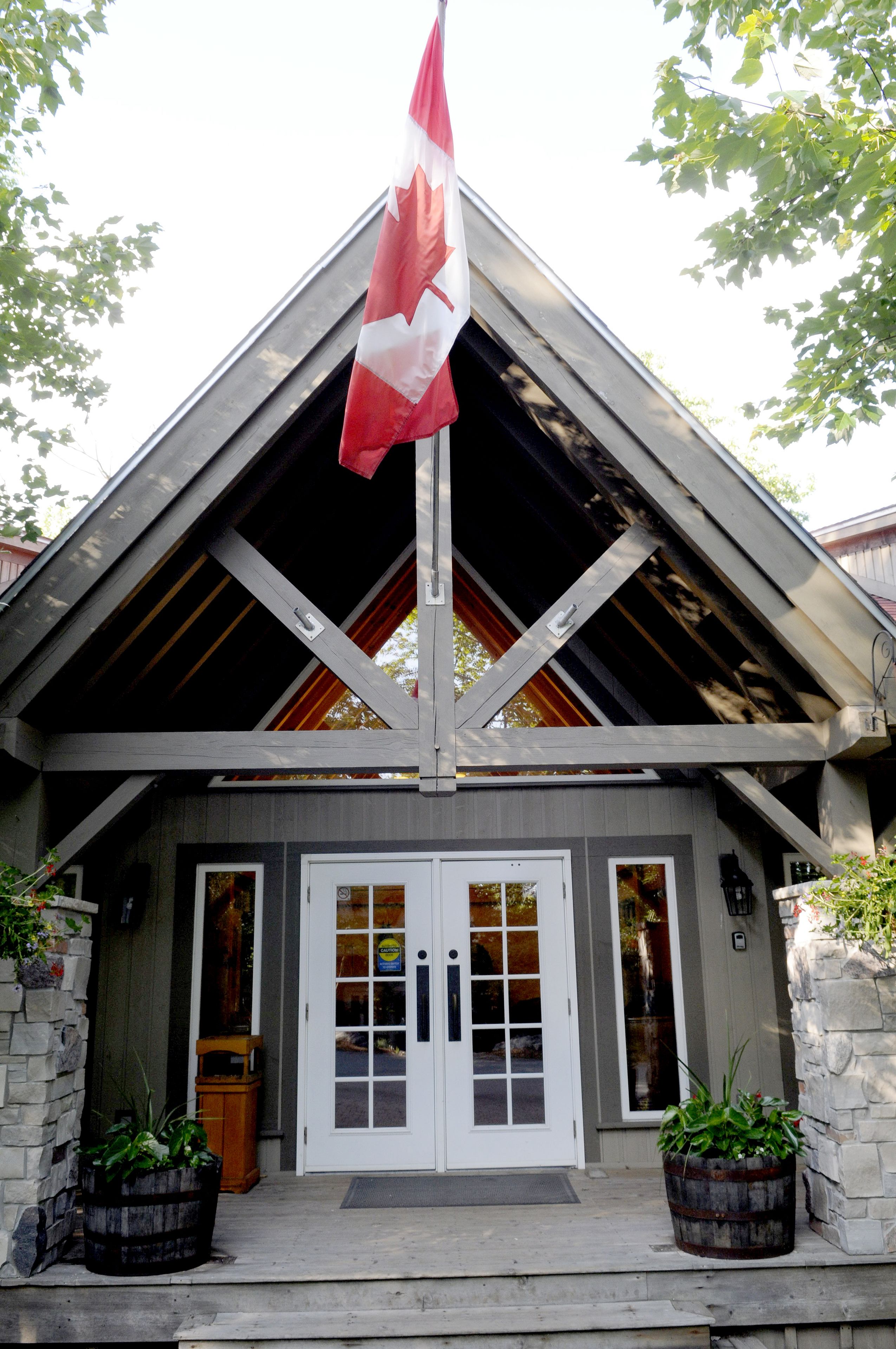 A building with a gabled roof, a flagpole with a flag, and a double door entrance.