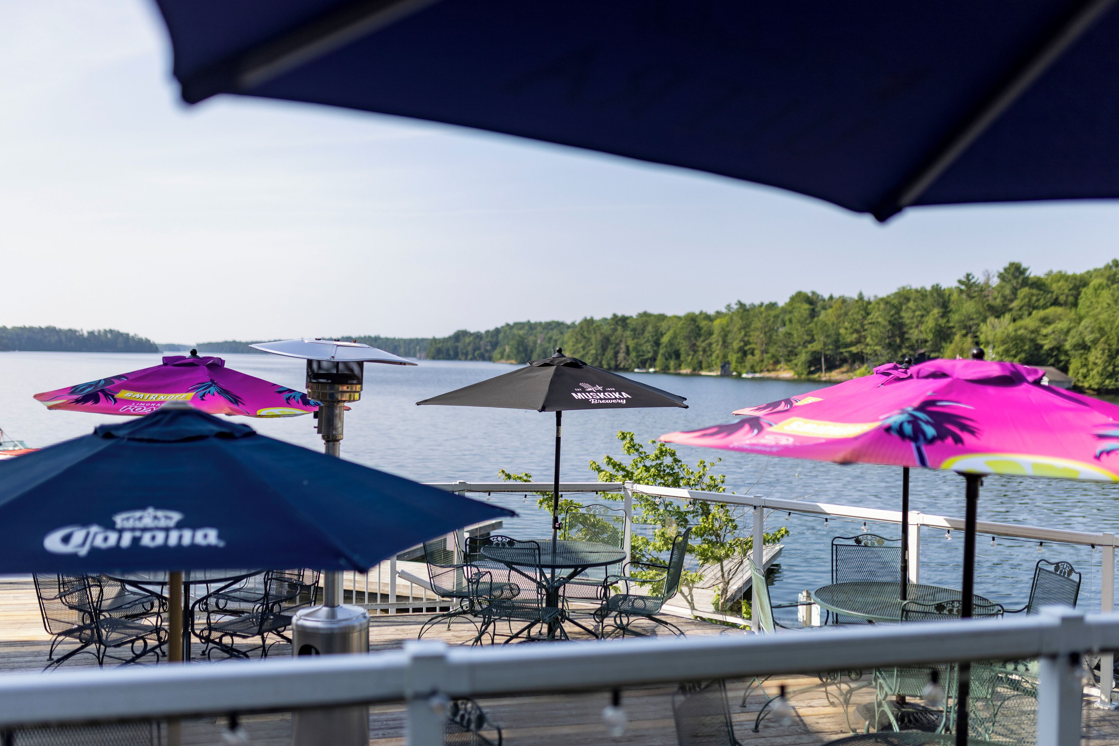 A deck with outdoor seating and umbrellas, overlooking a lake.