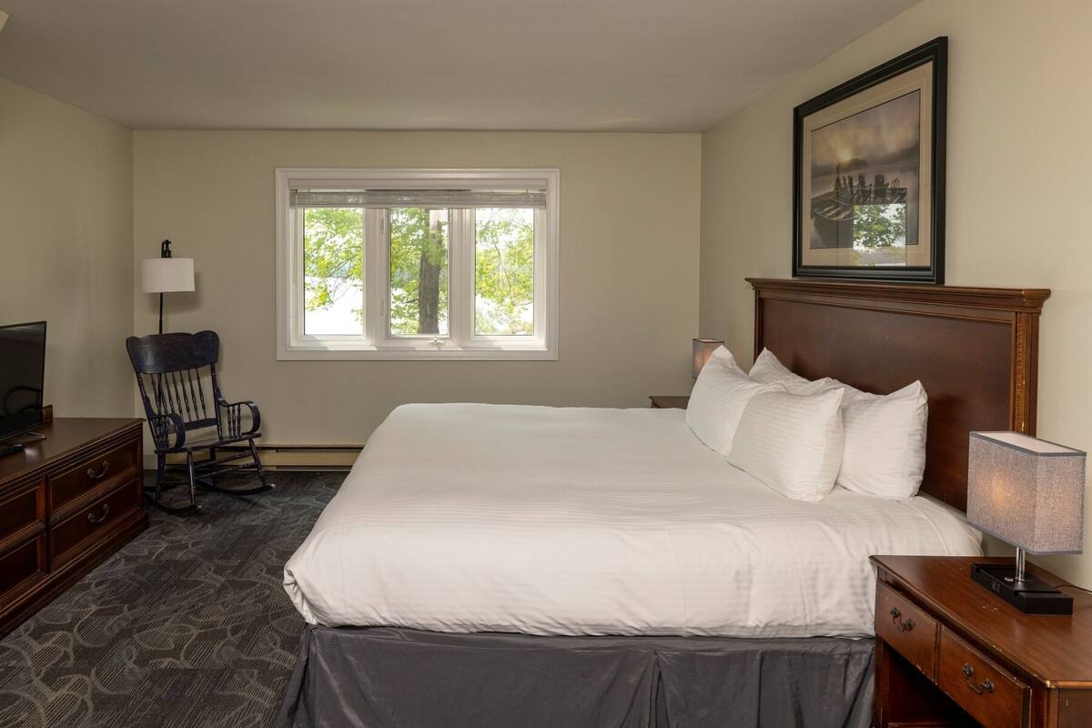 A neatly arranged hotel room with a large bed, a desk, a chair, and a television.