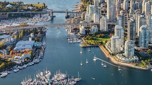 Paisagem costeira com um porto repleto de barcos, edifícios residenciais altos e uma ponte ligando duas áreas.
