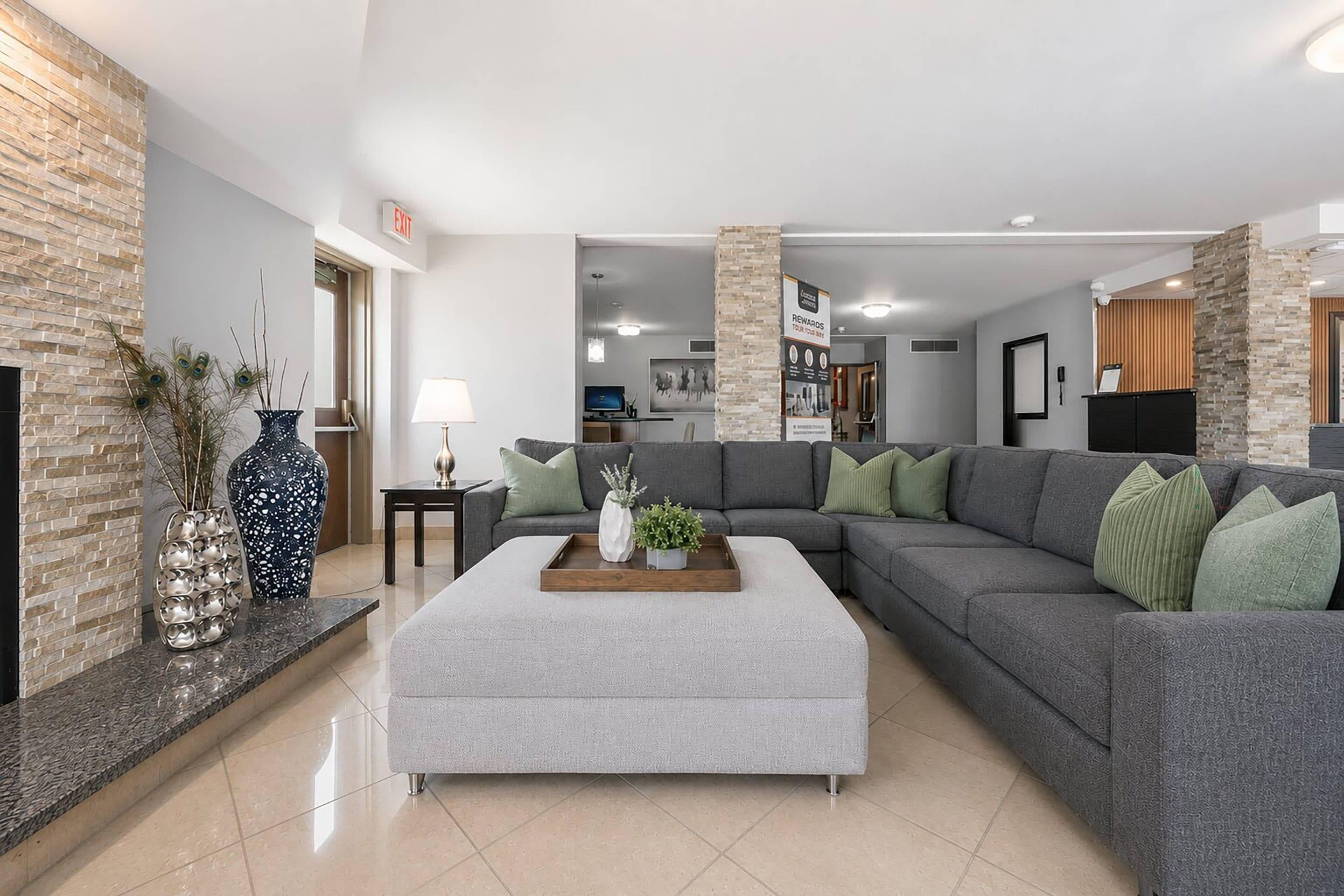 A modern living room with a grey sectional sofa, a coffee table, and decorative vases.