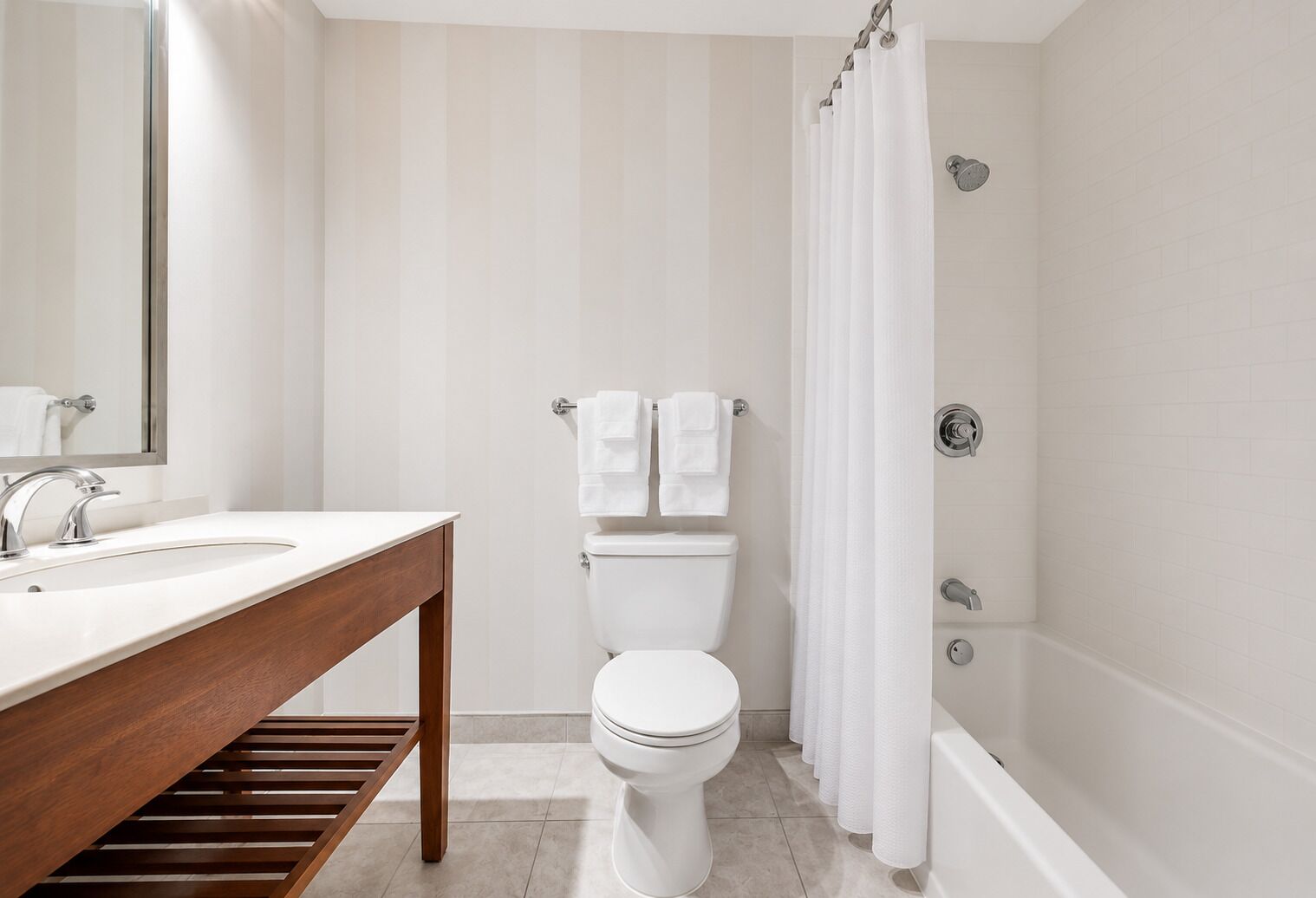 Un baño con tocador de madera, inodoro, ducha con cortina y espejo.