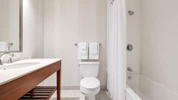 Un baño con tocador de madera, inodoro, ducha con cortina y espejo.