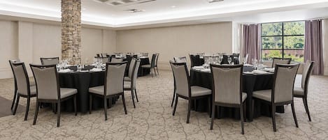 A conference room with round tables, chairs, and a stone pillar.