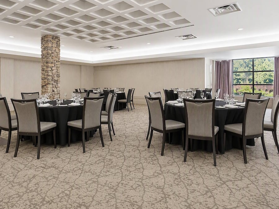 A conference room with round tables, chairs, and a stone pillar.