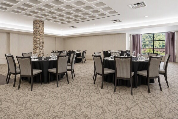 A conference room with round tables, chairs, and a stone pillar.