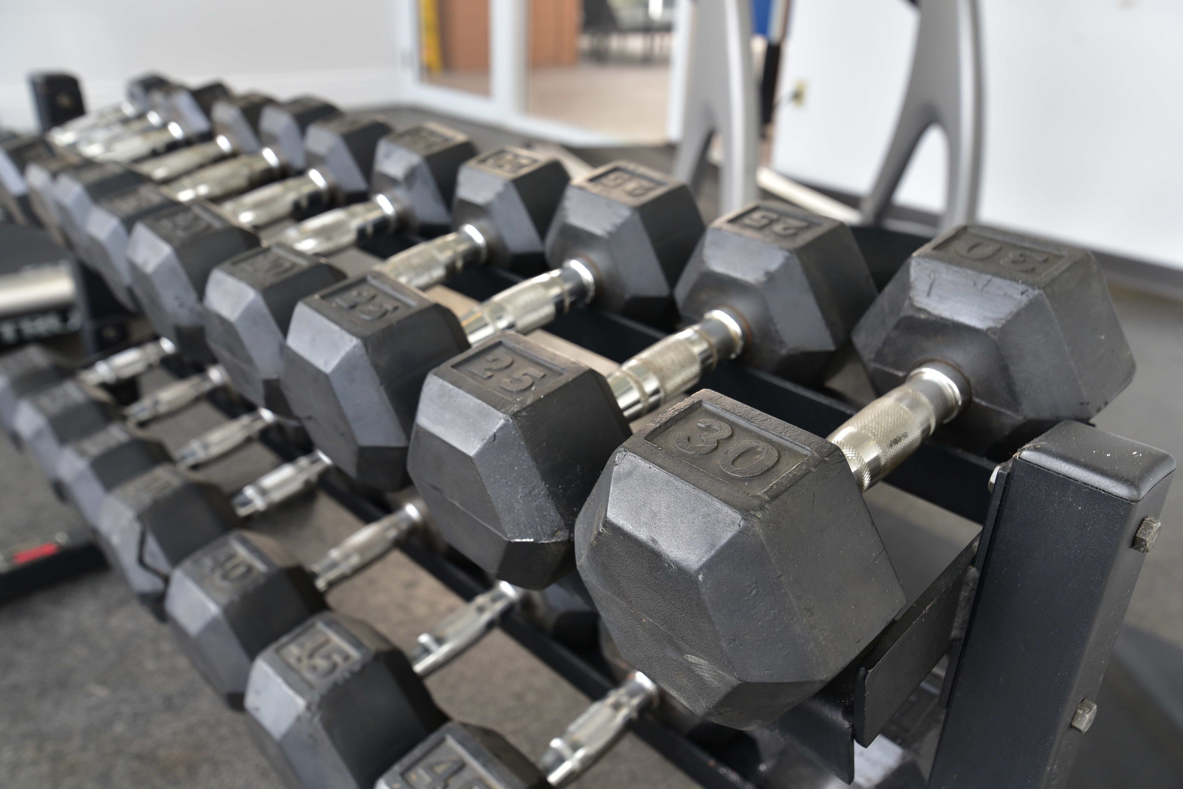 A set of hexagonal dumbbells with weight markings, arranged on a rack.