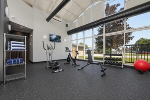 A gym with exercise equipment, a TV, and a large window with a view of the outdoors.