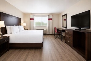 A hotel room with a bed, desk, chair, television, and a dresser. - Quality Inn and Conference Centre (Pembroke)