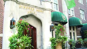 L’entrée de l’hôtel Windsor Arms, avec sa façade classique, ses grands pots de plantes et ses auvents verts.