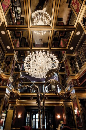 A grand interior with ornate chandeliers, a large mirror, and a staircase. - Windsor Arms Hotel (Toronto)