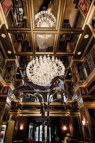 A grand interior with ornate chandeliers, a large mirror, and a staircase.