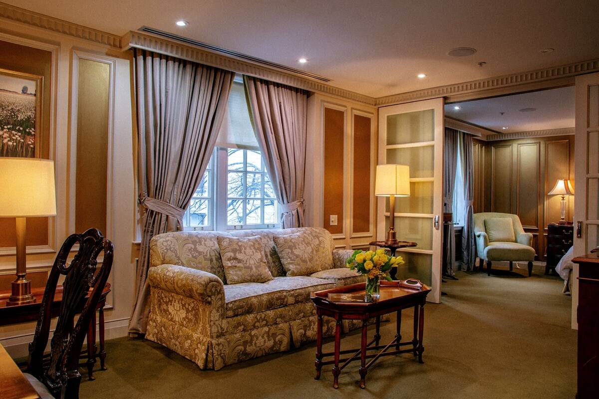 Un salon bien éclairé, avec un canapé, une table ornée d’un vase de fleurs et un fauteuil.