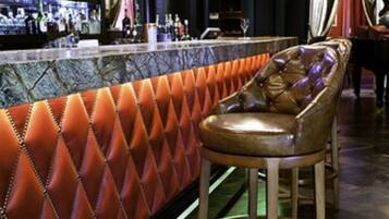 A bar area with a leather bar stool, a marble countertop, and a chandelier.
