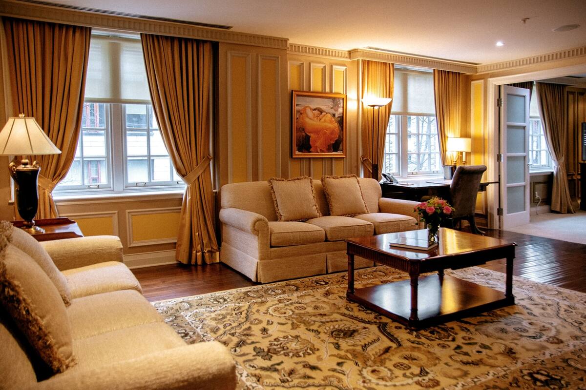 Un salon spacieux avec un ensemble de canapés beige, une table basse et un grand tapis à motifs.