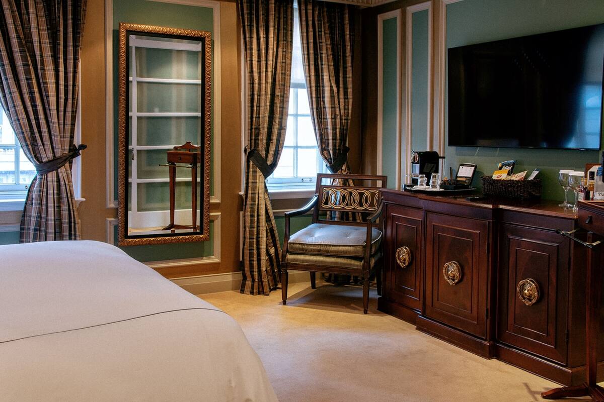 Une chambre d’hôtel avec un grand lit, une armoire en bois, une télévision et une chaise.