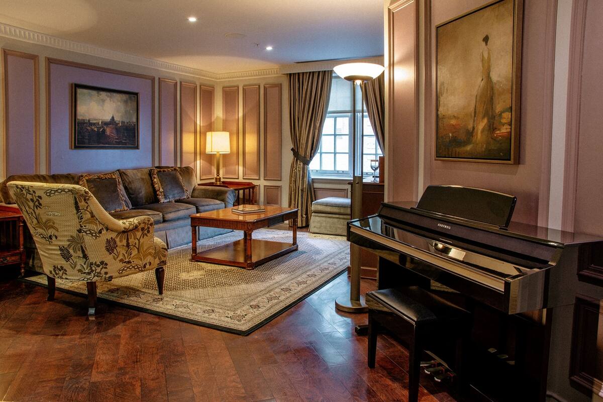 Un salon spacieux comprenant un canapé, un fauteuil, une table basse et un grand piano.