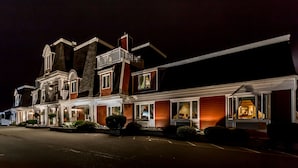 A two-story hotel with a traditional architectural style, featuring a prominent balcony and a well-lit entrance. - Inn on the Lake (Fall River)