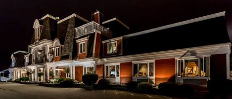 A two-story hotel with a traditional architectural style, featuring a prominent balcony and a well-lit entrance.