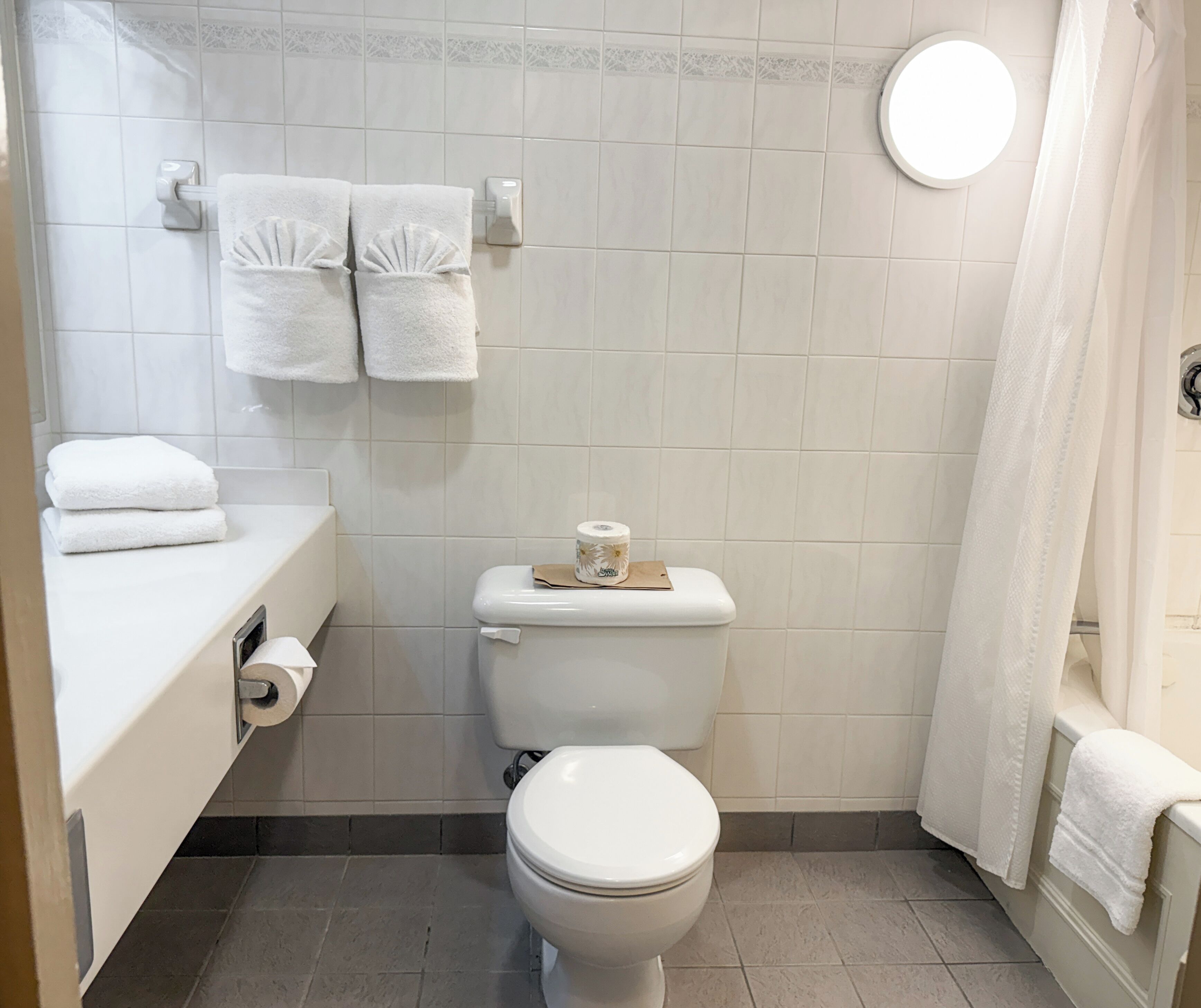 A bathroom with a toilet, a sink with a towel dispenser, and a shower curtain.