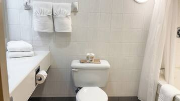 A bathroom with a toilet, a sink with a towel dispenser, and a shower curtain.