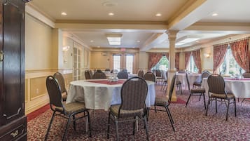 A banquet hall with round tables, chairs, and a carpeted floor.