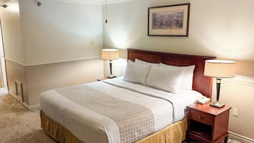 A neatly made bed with a wooden headboard, two bedside lamps, and a ceiling fan.