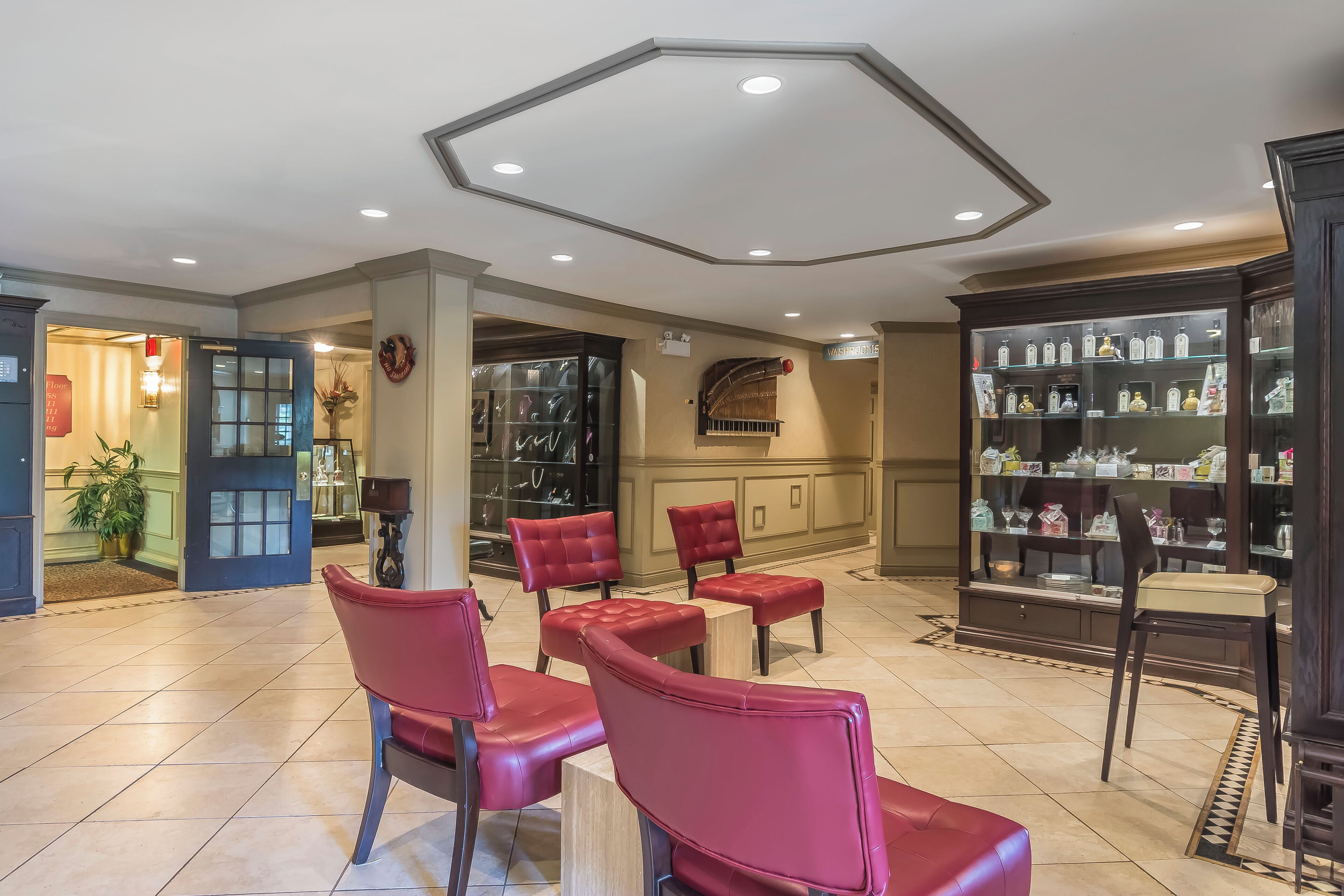 A hotel lobby with red leather chairs, a glass display case, and a reception area.