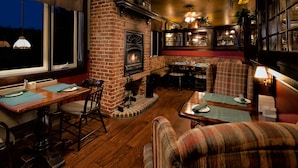 A cozy interior with a brick fireplace, wooden flooring, and plaid furniture. - Inn on the Lake (Fall River)