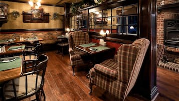 Interior acogedor de un restaurante con pisos de madera, sillas a cuadros y una chimenea de ladrillo.