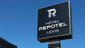 Une enseigne pour l’hôtel Repotel Levis, avec un bâtiment moderne en arrière-plan.