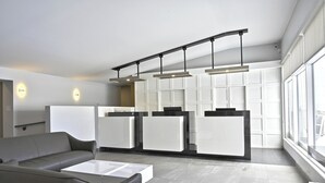 Une cuisine moderne avec des meubles blancs, un canapé gris et des luminaires suspendus.