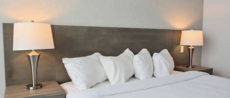 A neatly made bed with white bedding, two bedside lamps, and a modern headboard.