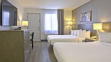 A hotel room with two beds, a desk, a TV, a door, and a window with curtains.