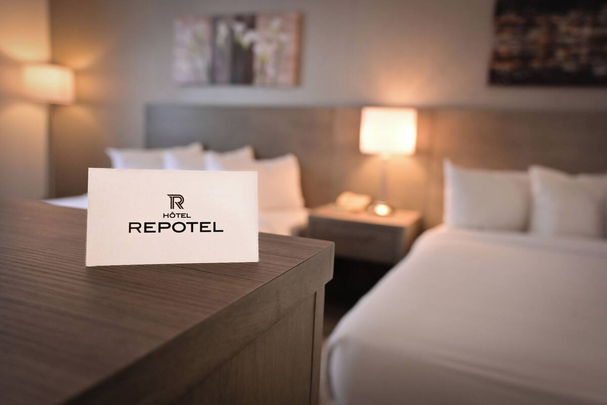 A hotel room with a neatly made bed, a bedside table, a lamp, and a wall-mounted artwork.