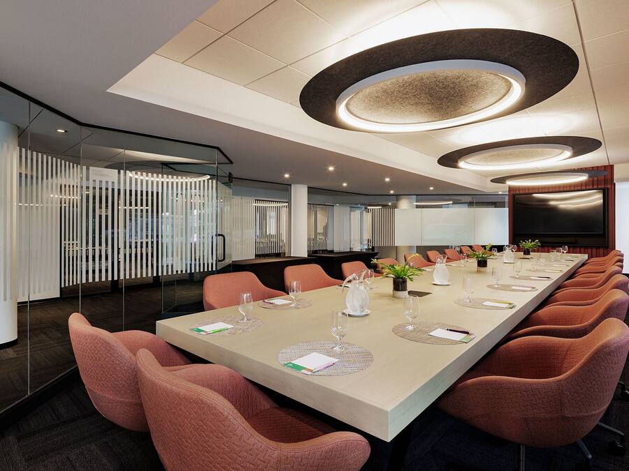 Une salle de conférence avec une longue table, des chaises et un grand écran.
