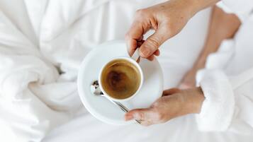 Une personne tenant une tasse de café sur une assiette blanche.