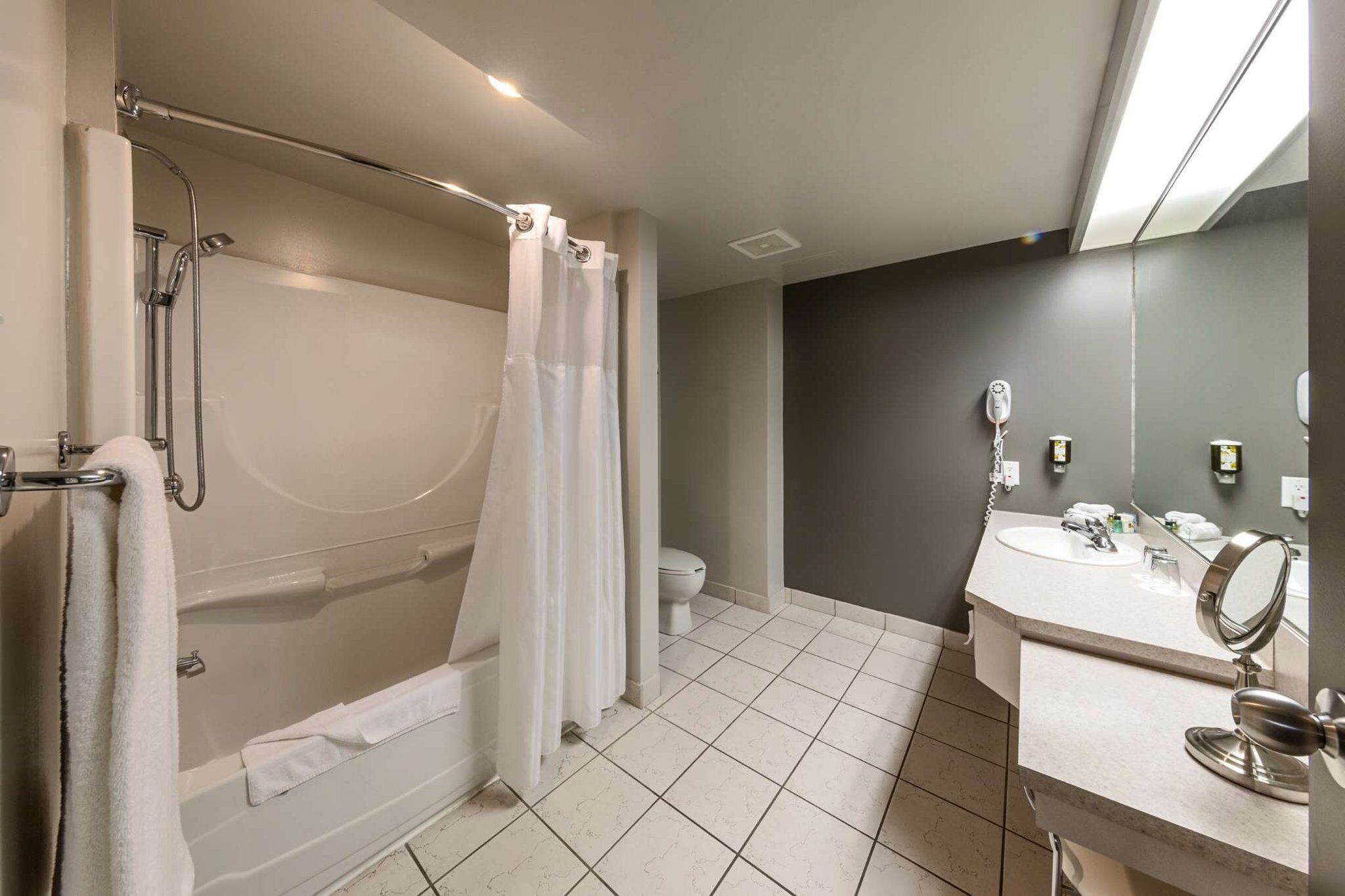 A modern bathroom with a bathtub, shower, toilet, and a vanity with a mirror.