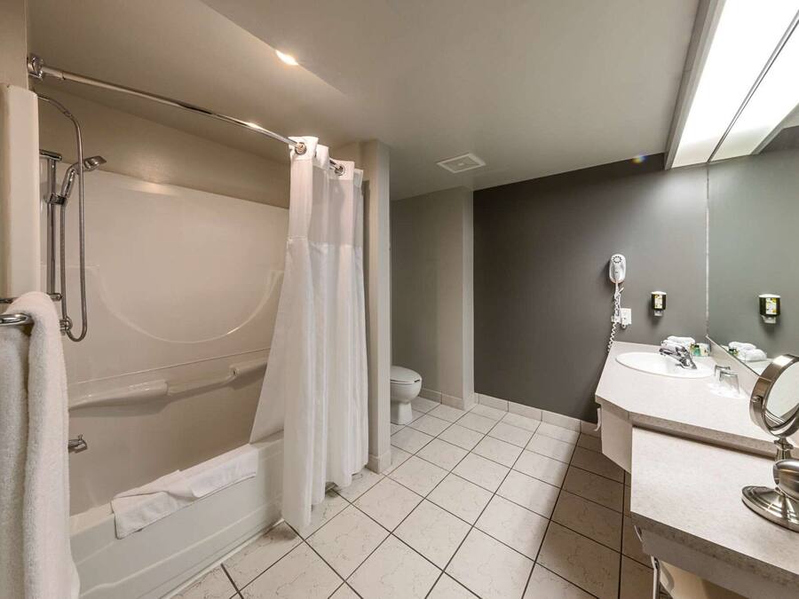 A modern bathroom with a bathtub, shower, toilet, and a vanity with a mirror.